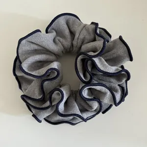 Detail of grey wool scrunchie with contrasting navy blue stitched edges and wavy texture