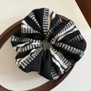 Dettaglio di scrunchie in maglia a righe con etichetta fatta a mano su vassoio in legno