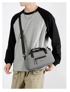 Détail du sac bandoulière en nylon gris montrant la sangle réglable et la poche zippée avant
