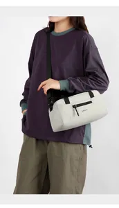 Détail de la bandoulière réglable sur un sac bandoulière gris clair en nylon imperméable