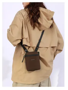 Detail of dark brown nylon crossbody bag with adjustable strap and front logo