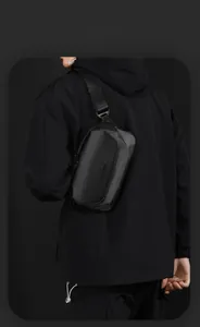 Detail of a sleek black waterproof crossbody bag featuring a secure magnetic buckle