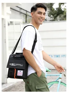 Action shot of a men's waterproof black messenger bag featuring orange accents and brand logo