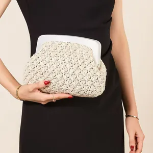 Detail view of an elegant beige woven evening clutch bag with a white acrylic frame