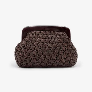 Detail view of a brown woven evening clutch bag with a sleek acrylic clasp.