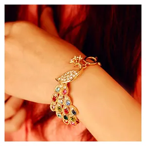 Elegant gold peacock bracelet featuring colorful crystals and rhinestones on model's wrist