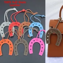 Detail of horseshoe-shaped full grain cowhide charms in multiple colors on a leather bag