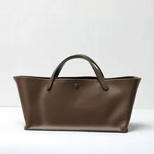 Minimalist wide brown leather tote bag featuring a vintage design and sturdy handles