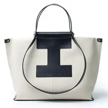 Front view of a white leather tote bag featuring a black I-shaped leather patch.
