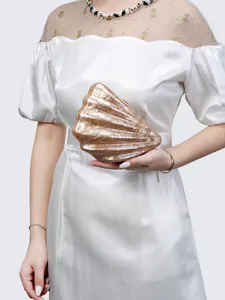 Detail shot of the shell-shaped champagne acrylic clutch bag with pearl luster texture