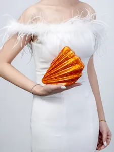 Detail of vibrant orange shell-shaped acrylic clutch bag with marble texture finish