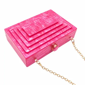 Detail view of hot pink layered acrylic evening clutch bag with elegant gold chain strap