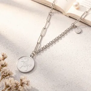 Close-up of asymmetrical stainless steel necklace with cartoon pony and S letter charms