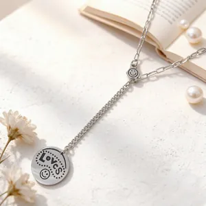Detail of silver Y-shaped necklace with smiley face charm and engraved Loves pendant
