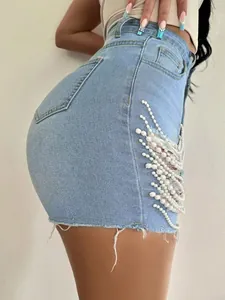 Détail de short en jean taille haute avec perles blanches et bords francs effilochés