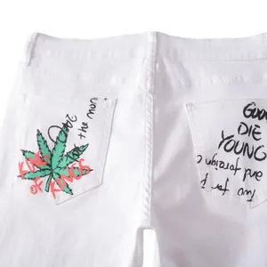 White street style jeans featuring green leaf print and graffiti on back pockets