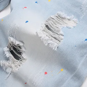 Slim fit light blue denim shorts with distressed rips and multi-colored paint splatter
