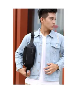 Close-up of black waterproof nylon sling bag for men worn over a denim jacket