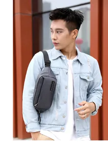 Close-up of grey waterproof nylon chest bag with adjustable strap on male model