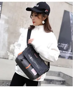 Modelo de estilo callejero con bolso bandolera de nailon negro y detalles naranjas