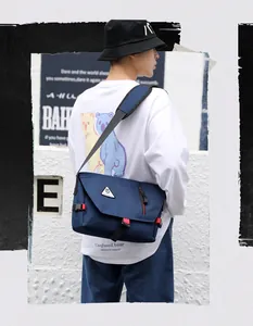 Detail of navy blue waterproof oxford messenger bag with buckle and red strap accents