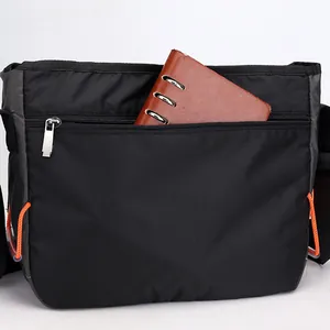 Bandolera versátil de nailon negro con bolsillo de cremallera y detalles en naranja