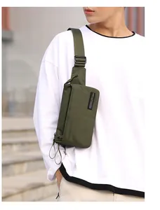 Side view of army green nylon crossbody bag worn by a model in an urban setting