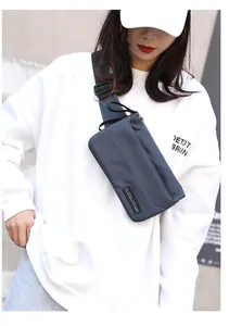 Close-up of blue crossbody bag with adjustable strap and metal zippers worn by model