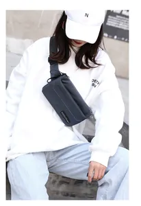 Close-up of a dark grey nylon crossbody chest bag featuring adjustable straps and zipper pockets