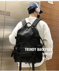 Male model wearing a black nylon backpack with cross-elastic cords and chest buckle straps