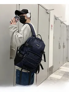 Man wearing a large navy blue commuter backpack with cross elastic cords in a modern corridor