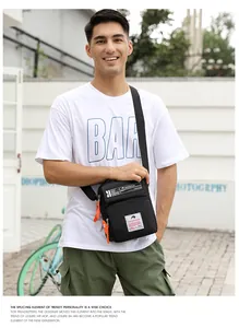 Détail du sac bandoulière en nylon noir avec tirette orange et sangle logotypée élégante