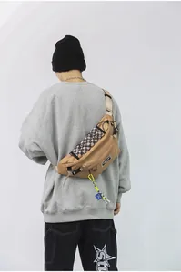 Detailweergave van kaki crossbodytas met geblokte zak en neon klimhaak voor heren