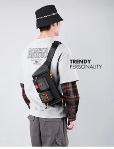 Detail view of black functional crossbody bag featuring orange zipper accents on a male model