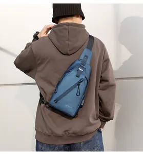 Sac bandoulière bleu étanche avec port USB porté par un modèle masculin en extérieur