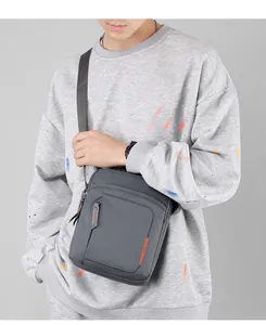 Detalle de bandolera impermeable gris oscuro con logotipo WEPOWER naranja de estilo urbano