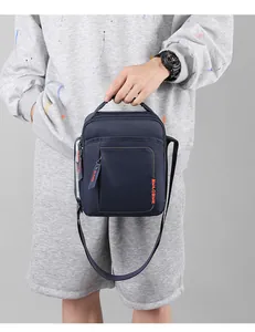 Detalle del bolso bandolera de nailon azul con correa ajustable y logo naranja
