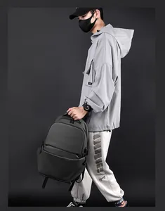 Détail d'un sac à dos gris foncé avec poche zippée latérale et logo texturé discret