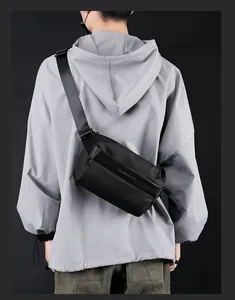 Detail of adjustable woven strap and metal logo on waterproof black crossbody chest bag
