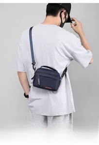 Détail de la sacoche en nylon bleu marine imperméable avec logo orange et fermetures