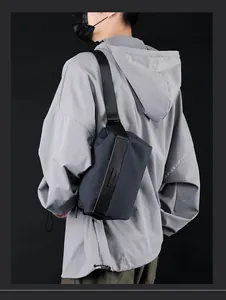 Modern tactical chest bag in dark gray blue waterproof fabric worn by a male model