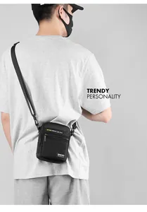 Detail of black waterproof nylon crossbody bag showing zippers and brand text
