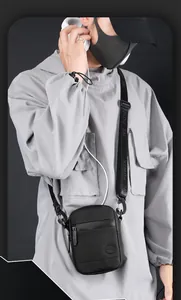 Detail of compact black crossbody bag with adjustable lettered strap and matte finish