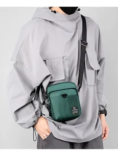 Detailed view of dark green nylon crossbody bag with functional zippers and strap