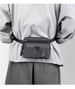 Detail of dark grey nylon multi-functional waist bag with zippers and D-ring hook on model