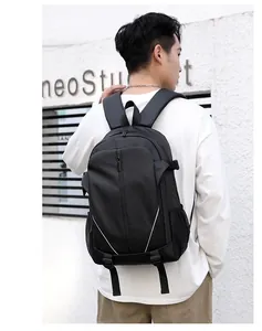Outdoor view of a black water-resistant backpack showing side mesh pocket and zip features