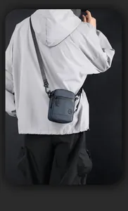 Rear view of a man wearing a dark blue mini crossbody bag with adjustable strap details