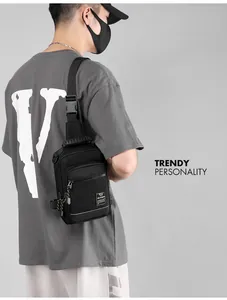 Detail view of black nylon chest bag with brand label and buckle on gray background
