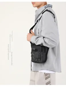 Détail d'un sac de poitrine tactique noir avec motifs camouflage gris et anneaux en D