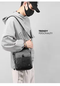 Borsa a tracolla da uomo in grigio e nero con motivo mimetico indossata dal modello